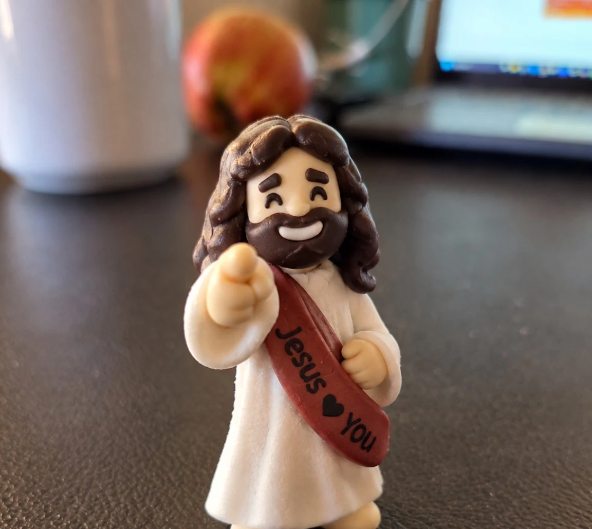 Smiling handcrafted Jesus figure pointing toward the viewer